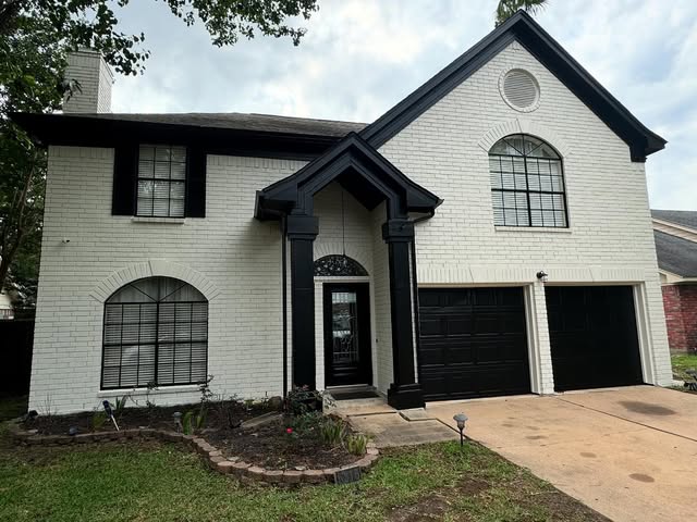 Two-story home after a full exterior repaint in white with black trim