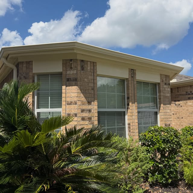 Brick home with freshly repainted fascia, soffit and gutters over tidy landscaping