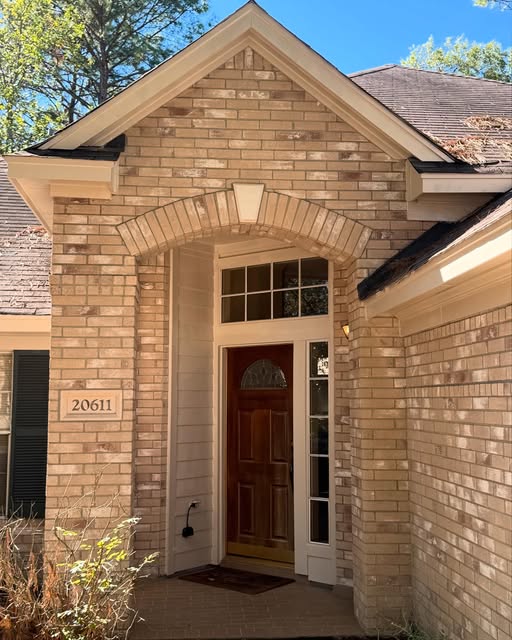 Refinished wood front door in an arched brick entry