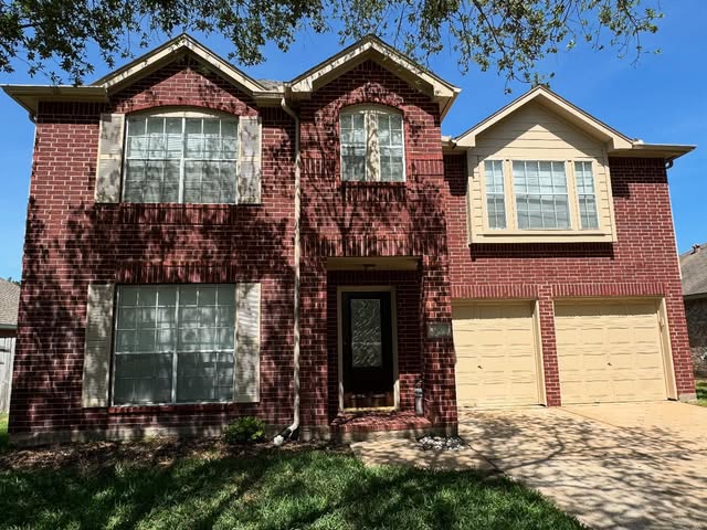 Two-story red brick home with repainted upper siding, shutters, trim and garage doors